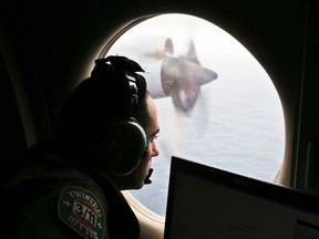 In this March 22, 2014 file photo, flight officer Rayan Gharazeddine scans the water in the southern Indian Ocean off Australia from a Royal Australian Air Force AP-3C Orion during a search for the missing Malaysia Airlines Flight MH370. A ship involved with the deep-sea sonar search for missing Malaysia Airlines Flight 370 is being fitted with equipment to examine several sonar contacts of interest on the remote seabed west of Australia, the Australian Transport Safety Bureau said on Wednesday, Oct. 19, 2016. (AP Photo/Rob Griffith, File)