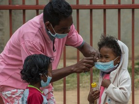Face masks are placed on children in Antananarivo, Madagascar, Tuesday, Oct. 3, 2017. (AP Photo/Alexander JOE)