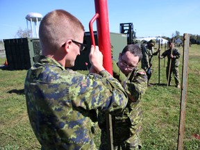 Elliot Ferguson/The Whig-Standard
Corporals Matthew Spooner, left, and Corey Salter set up a fence post during an exercise by the Canadian Forces Joint Operational Support Group at Canadian Forces Base Kingston on Tuesday.