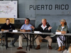President Donald Trump and first lady Melania Trump participate in a briefing on hurricane recovery efforts with first responders at Luis Muniz Air National Guard Base, Tuesday, Oct. 3, 2017, in San Juan, Puerto Rico as Puerto Rico Gov. Ricardo Rosselló, left of the President, looks on. (AP Photo/Evan Vucci)
