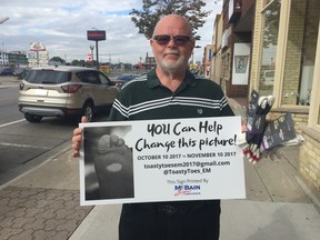 Richard Stewart holds up a sign advertising the ToastyToes for St. Thomas Elgin-Middlesex and London campaign that runs from Oct. 10 to Nov. 10. The campaign will collect warm socks to donate to people in need. (Laura Broadley/Times-Journal)