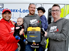 Sav Neth (left) and Logan Neth, Patrick Taylor and Jordan Neth, and Alex Davy hold an Automated Electronic Defibrillator at Middlesex-London EMS headquarters. Sav, Patrick, and Alex are members of Dad Club London, a local support group that recently gifted the Thames Valley District School Board with $50,000 to place AEDs in schools. (Chris Montanini\Londoner)