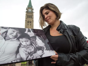Rachel Quinn, the adoptive mother of Joshua holding a photo of Mary Papatsie, Joshua Papatsie Quinn, with her on the right while attending the 12th annual gathering of the Families of Sisters in Spirit, a group that formed to draw attention to murdered and missing indigenous women.  Photo Wayne Cuddington/ Postmedia