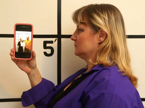 Cathy Boretski poses at her 'mugshot'' wall at her Orleans B&B with the photo she took of two alleged scammers.