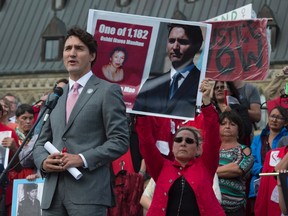 Maggie Cywink, centre right, of Whitefish River First Nation, holds up a sign behind Prime Minister Justin Trudeau as he speaks during the Families of Sisters in Spirit Vigil in support of missing and murdered indigenous women on the steps of Parliament Hill in Ottawa, Wednesday, October 4, 2017. THE CANADIAN PRESS/Adrian Wyld