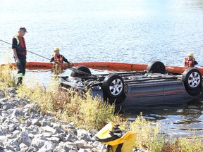 Jason Miller/The Intelligencer
Firefighters cordon off an area around a car which ended up in the Moira River following a crash Wednesday evening. The vehicle was removed from the water early Thursday.