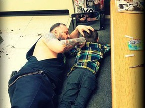 This handout photo, posted online last week, shows Francis "Franz" Jacob lying on the floor of his Rouyn-Noranda shop as he gives a young boy named Wyatt a haircut. THE CANADIAN PRESS/HO-Franz Jacob