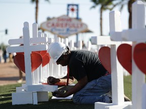 Greg Zanis writes the name of a victim of Sunday's mass shooting as he places crosses near the city's famous sign Thursday, Oct. 5, 2017, in Las Vegas. (AP Photo/Gregory Bull)
