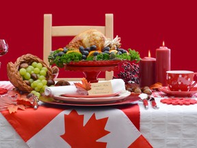 Red and white Canadian theme Thanksgiving table setting with flag and roast turkey on large platter centerpiece.