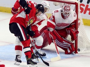 Ottawa Senators' Ryan Dzingel (18) and Detroit Red Wings' Trevor Daley (83) vie for the puck as Red Wings goaltender Jimmy Howard (35) looks on during second period NHL hockey in Ottawa, Saturday, October 7, 2017. (THE CANADIAN PRESS/Fred Chartrand)