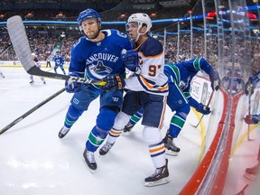 Vancouver Canucks' Alexander Edler, left, of Sweden, checks Edmonton Oilers' Connor McDavid during the first period of an NHL hockey game in Vancouver on Saturday. (THE CANADIAN PRESS/Darryl Dyck)