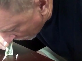 Miami Dolphins offensive line coach Chris Foerster appears to be snorting three lines of a white powdery substance at a desk. (YouTube screen grab)