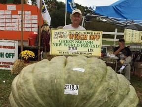 In this Oct. 7, 2017, photo provided by Susan Jutras, Joe Jutras stands with his world record breaking, 2,118-pound squash, following a weigh-in at Frerichs Farm in Warren, R.I. (Susan Jutras via AP)
