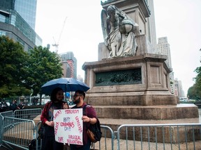 Two protesters display a placard under the statue of Christopher Columbus at the Columbus Circle in New York on October 9, 2017, calling for the removal of the statue. (Jewel Samad/Getty Images)