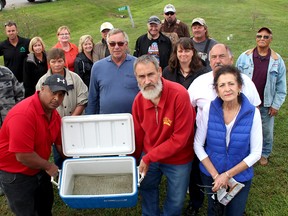 Calvin Simmons, front left, and Water Wells First spokesperson, Kevin Jakubec, second from left, display the sediments found in water taken from Simmons' well, during a press conference held at Simmons' home north of Chatham. The citizens’ group says wells continue to experience problems when pile driving takes place nearby for the construction of wind turbines for the North Kent Wind project. Also pictured are other property owners who have seen their wells go bad after pile driving took place near their properties.