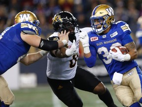 Winnipeg Blue Bombers' Andrew Harris attempts to get around Hamilton Tiger-Cats' Davon Coleman during the second half of CFL action in Winnipeg on Oct. 6, 2017. (THE CANADIAN PRESS/John Woods)
