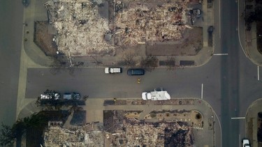 In this aerial image people look at homes that were destroyed by a wildfire in Santa Rosa, Calif., Tuesday, Oct. 10, 2017. Newly homeless residents of California wine country took stock of their shattered lives Tuesday, a day after deadly wildfires destroyed homes and businesses. (Nick Giblin/DroneBase via AP)
