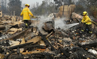 Firefighters douse hot spots in the Coffey Park area of Santa Rosa, Calif., on Tuesday, Oct. 10, 2017. An onslaught of wildfires across a wide swath of Northern California broke out almost simultaneously then grew exponentially, swallowing up properties from wineries to trailer parks and tearing through both tiny rural towns and urban subdivisions. (AP Photo/Ben Margot)