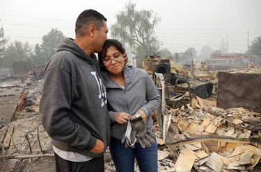 Jose Garnica, left, kisses his daughter Leslie Garnica in front of their home that was destroyed in the Coffey Park area of Santa Rosa, Calif., on Tuesday, Oct. 10, 2017. An onslaught of wildfires across a wide swath of Northern California broke out almost simultaneously then grew exponentially, swallowing up properties from wineries to trailer parks and tearing through both tiny rural towns and urban subdivisions. (AP Photo/Ben Margot)