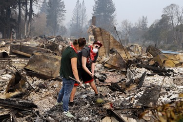 Robyn & Daniel Pellegrini search for belongings in the ashes of their home that was destroyed by fire in the Coffey Park area of Santa Rosa, Calif., on Tuesday, Oct. 10, 2017. An onslaught of wildfires across a wide swath of Northern California broke out almost simultaneously then grew exponentially, swallowing up properties from wineries to trailer parks and tearing through both tiny rural towns and urban subdivisions. (AP Photo/Ben Margot)
