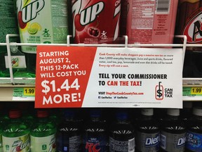 In this on Aug. 22, 2017 file photo, a sign sponsored by opponents of the new Cook County tax on sweetened beverages is posted in the soda isle of Tischler Finer Foods in Brookfield, Ill. (AP Photo by Sara Burnett File)