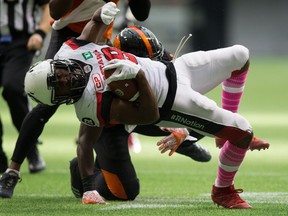 Ottawa Redblacks' William Powell, front, dives past B.C. Lions' Micah Awe while carrying the ball during the first half of a CFL game in Vancouver on Oct. 7, 2017. (THE CANADIAN PRESS/Darryl Dyck)