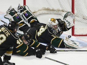 Jason Kryk/postmedia news
London Knights goalie Tyler Johnson and teammates dive to deny a Spitfires chance during the first period of their OHL game at the WFCU Centre in Windsor on Thursday night. The Spitfires scored twice late to win 3-1.