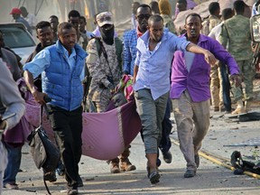 Somalis use a sheet to carry a man wounded in a blast away to an ambulance, in the capital Mogadishu, Somalia Saturday, Oct. 14, 2017. A huge explosion from a truck bomb has killed at least 20 people in Somalia's capital, police said Saturday, as shaken residents called it the most powerful blast they'd heard in years. (AP Photo/Farah Abdi Warsameh)