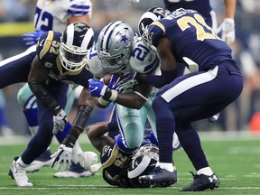 Ezekiel Elliott #21 of the Dallas Cowboys is hit by Alec Ogletree #52 and Kayvon Webster #21 of the Los Angeles Rams on a carry in the first quarter of a football game at AT&T Stadium on October 1, 2017 in Arlington, Texas. (Photo by Ronald Martinez/Getty Images)