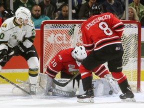 Knights Adrian Carbonara tries to get his stick free to jam a puck past Owen Sound goaltender Zack Bowman during their game at Budweiser Gardens on Sunday October 15, 2017. Alan Lyszczarczyk of the Attack is coming back to help. (MIKE HENSEN, The London Free Press)