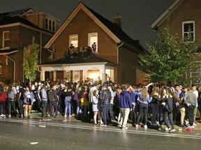 A large crowd gathers outside a house at 393 Brock St. during a Queen's Homecoming party early Sunday morning. (Steph Crosier/The Whig-Standard)