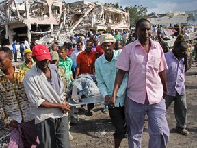 Somalis remove the body of a man killed in Saturday's blast, in Mogadishu, Somalia Sunday, Oct. 15, 2017. (AP Photo/Farah Abdi Warsameh)