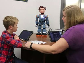 Logan, a Grade 3 student at St. Michael Catholic School in Belleville, works with Jada Amo, an applied behaviour analysis adviser with the Algonquin and Lakeshore Catholic District School Board, and Milo, a robot designed to help students with autism spectrum disorder. (BRUCE BELL/Postmedia Network)