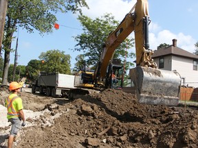 Kyle Schonauer, left, watches overhead wires while Craig Joris moves dirt on Emma Street in Sarnia in August. The workers with Van Bree Drainage and Bulldozing were completing part of a $4.9-million sewer separation project. (Tyler Kula/Sarnia Observer)
