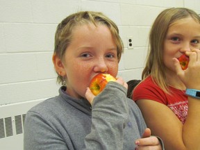 Hunter McKenny, left, and Sidney Childs, both age 10 and in Grade 5, take a bite of apples Thursday in the gym at Col. Cameron Public School in Corunna during its Great Big Crunch event. It's held annually to celebrate the student nutrition program offered to more than 8,300 students at 42 Lambton County schools. (Paul Morden/Sarnia Observer)