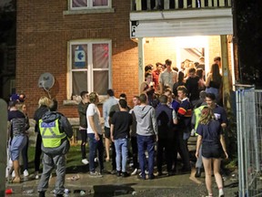Kingston Police peer up at a male on the peak of an Earl Street house during Queen's Homecoming last weekend. (Steph Crosier/The Whig-Standard)