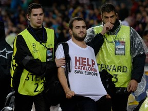 A man sporting a T-shirt demanding help for Catalonia is taken of the field by security during the UEFA Champions League group D soccer match between FC Barcelona and Olympiacos FC in Barcelona Wednesday. While some people in Quebec and Catalonia feel their region is homogeneous enough to separate from Canada and Spain, others would beg to differ. (JOSEP LAGO/AFP)
