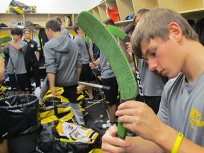Kaden Babcock and other players with the Lambton Jr. Sting Minor Midget AAA team, put green tape on their hockey sticks before a game Sunday at the Progressive Auto Sales Arena in Sarnia. The tape matches the green ribbon symbol for mental health awareness. The team is part of a Faceoff for Mental Health campaign involving hockey groups in Sarnia-Lambton and St. Clair Child and Youth Services.
 Paul Morden/Sarnia Observer/Postmedia Network