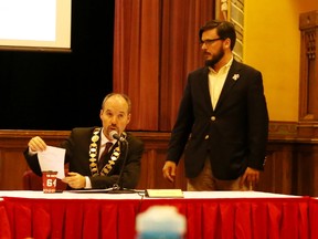 Kingston Mayor Bryan Paterson, left, reads out an amendment from Sydenham District Coun. Peter Stroud at a city council meeting on Oct. 17. (Elliot Ferguson/The Whig-Standard)
