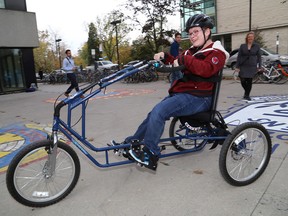 Janessa Gerhardt, 18, of Napanee demonstrates her adapted bicycle outside of Botterell Hall at Queen's University as Claire Davies of the Building and Designing Assistive Technology Lab looks on on Monday October 23 2017.  Ian MacAlpine /The Whig-Standard/Postmedia Network