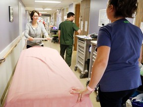 Luke Hendry/The Intelligencer
Quinte health care hospitality services representative Andrea Taylor, foreground, and registered nurse Courtney Crumb move a stretcher on the Quinte 5 inpatient floor of Belleville General Hospital Monday. The corporation is receiving funding to open 15 beds to ease capacity issues. In the background is registered practical nurse David Thompson.