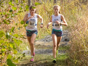 Anna Workman, left, and Mackenzie Campbell of the Kingston Blues run side by side through a muddy section of the course during the junior girls race at the Kingston Area Secondary Schools Athletic Association cross-country championships at the Little Cataraqui Creek Conservation Area this past Thursday. (Tim Gordanier/The Whig-Standard)