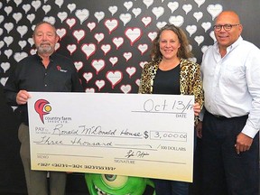 Grant Watson (left) and Blake Patterson (right), from Country Farm Seeds Ltd. present a $3,000 cheque to Kelly Montfort, manager of development for the Ronald McDonald House Charities in London.