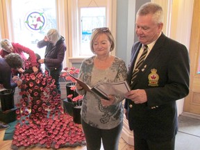 Sarnia potter Pauline Anderson looks over a list of names of Sarnia-area resident who died in war with Jim Burgess, president of the Royal Canadian Legion Branch 62, as potters, from left, Karen McGlughan, Brid Lachapelle and Stef Smalls assemble a memorial display of 300 handmade ceramic poppies in the lobby of the Lawrence House Centre for the Arts. (Paul Morden/Sarnia Observer/Postmedia Network)