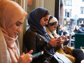 In this stock photo, a group of young Muslim women use their cellphones wearing hijabs. (Getty Images)