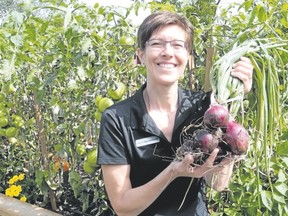 Debra Vandermeer of Simcoe shows off onions harvested in the summer from one of the community gardens established in the town by the local ecumenical group Church Out Serving. It?s an example of Christians working to reverse divisions in the church that go back hundreds of years. (Monte Sonnenberg/Postmedia File photo)