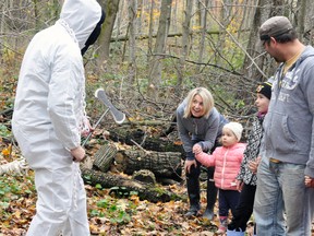 The Michel family, of Mitchell, including mom Kristi (left), two-year-old Riya, Zoey and Elden, met up with this scary executioner (Garry Vivian) during the 8th annual Optimist Club of Mitchell Spooktacular event held Sunday afternoon at the Vorstenbosch bush just outside town. ANDY BADER/MITCHELL ADVOCATE