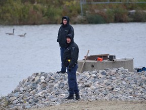 London police watch as water from a stormwater storage pond near Cudmore Crecent is drained Monday to allow investigators to search for evidence in the case of Josie Glenn. The remains of the 26-year-old London woman were found Friday in a home near the pond. A London man is charged with second-degree murder. (MORRIS LAMONT, The London Free Press)