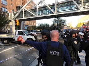 In this photo provided by the New York City Police Department, officers respond to a report of gunfire along West Street near the pedestrian bridge at Stuyvesant High School in lower Manhattan in New York, Tuesday, Oct. 31, 2017. (Martin Speechley/NYPD via AP)
