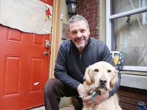 Dave Battaino cuddles with his daughter's dog Rosseau on Wednesday, after experiencing a harrowing situation the night before on Halloween. The Lloyd Street resident returned from trick or treating to find a stranger inside his home. He fought with the man and chased him through a downtown park before police finally apprehended the invader. (Gino Donato/Sudbury Star)